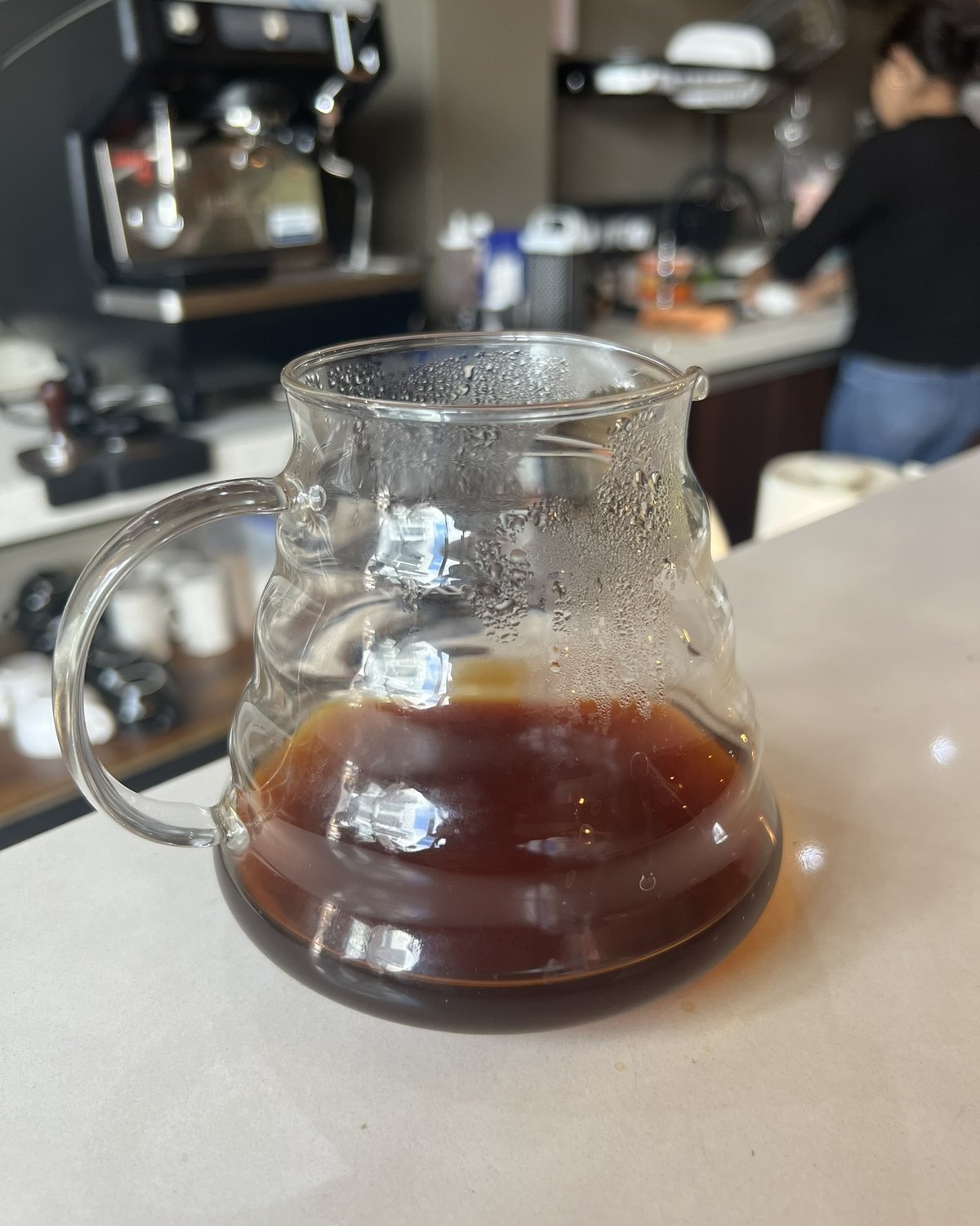 Freshly brewed filter coffee resting in a glass server at a coffee bar